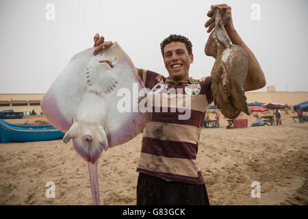 Ein Fischer bringt seinen frischen Fang an Land in Tifnit Strand in der Nähe von Agadir, Marokko. Stockfoto