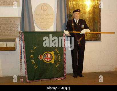 Ein Veteran, der den Standard der Malaya and Borneo Veterans Association trägt, mit einer neu enthüllten Gedenktafel. Stockfoto