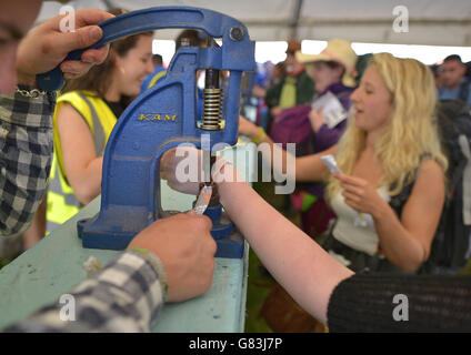 Festivalbesucher haben ihre Armbänder befestigt, wenn sie beim Glastonbury Festival auf der Worthy Farm in Somerset ankommen. Stockfoto