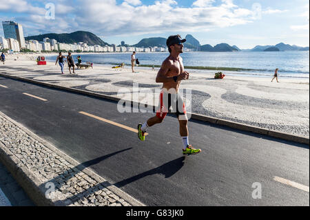 RIO DE JANEIRO - 3. April 2016: Eine junge Carioca brasilianischen Mann joggt entlang eine leere morgendliche Aussicht auf die Copacabana. Stockfoto