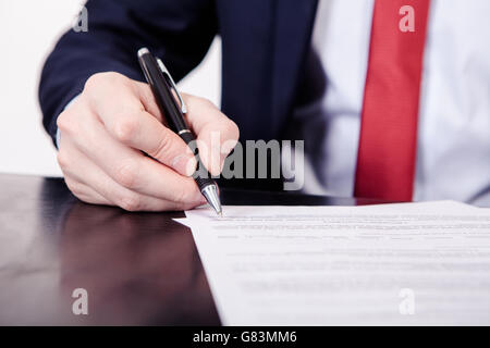 Geschäftsmann, die Unterzeichnung eines Vertrages. Eine Hand hält ein Füllfederhalter und einen Brief zu unterzeichnen. Styling und kleine Menge an Getreide angewendet. Stockfoto