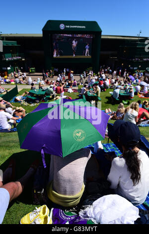 Am zweiten Tag der Wimbledon Championships am All England Lawn Tennis und Croquet Club in Wimbledon schützen sich die Zuschauer vor der Sonne auf Murray Mount. Stockfoto