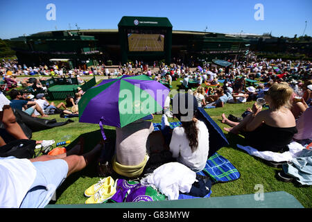 Am zweiten Tag der Wimbledon Championships am All England Lawn Tennis und Croquet Club in Wimbledon schützen sich die Zuschauer vor der Sonne auf Murray Mount. Stockfoto