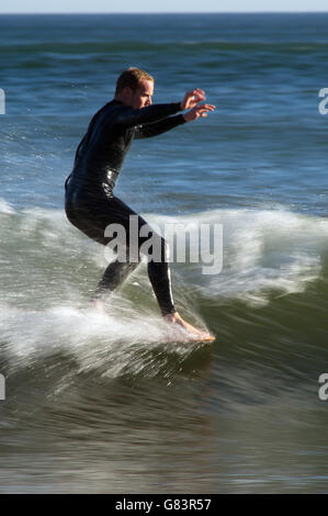 Hände hoch für Balance ein Surfer hängt, fünf auf die Spitze seiner Surf Board wie er Rennen über die Wandfläche der brechenden Welle Stockfoto