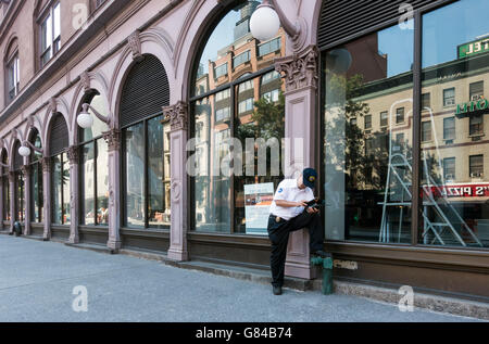 MTA Bus Manager überprüfen seinen Fahrplan vor der Foundation Building in der Nähe von Astor Place in der East Village, New York City Stockfoto