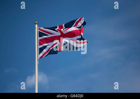 Union Jack-Flagge des Vereinigten Königreichs im Wind vor blauem Himmel. Stockfoto