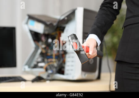 Computer absolut zerstört durch eine heißblütige Geschäftsfrau Hand einen hammer Stockfoto