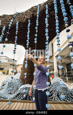 Rebecca Iveson 31 aus Bristol inspiziert Plastikflaschen, die am Schwanz eines Wals hängen, der Teil einer Skulptur von zwei lebensgroßen Walen aus Somerset-Weide und 70,000 Upcycling-Plastikflaschen ist, Das auf dem Millennium Square in Bristol enthüllt wurde, um den Status der Stadt als erste grüne Hauptstadt Großbritanniens zu markieren. Stockfoto