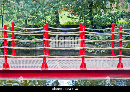 Fußgängerbrücke in Kunst aus Holz, rote Geländer gebaut und Hanf Seile in den Park von Pinocchio in Italien Stockfoto