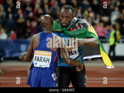 Der Brite Mo Farah gratuliert Jamaikas Usain Bolt zum Sieg beim 100-m-Finale der Männer am ersten Tag der Sainsbury's Anniversary Games im Stadion im Queen Elizabeth Olympic Park, London. Stockfoto