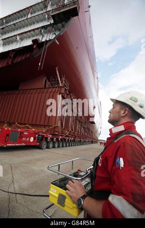 Operations Supervisor Joe Gilbert betreibt eine Steuereinheit, die zum ersten Mal einen 11,000-Tonnen-Abschnitt eines der im Bau befindlichen Flugzeugträger der Royal Navy aus der Hafenhalle der BAE Systems Govan Werft in Glasgow verlagern soll. Stockfoto