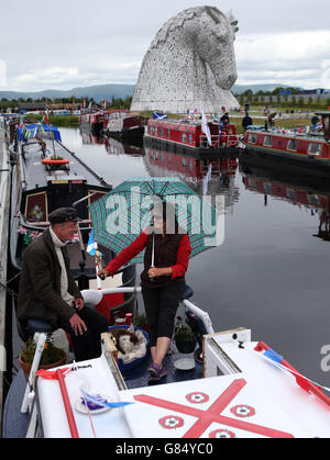 Die Bootsfahrer Dougie und Bernadette MacFarlane auf ihrer Barge Pendle vor den Kelpies am Forth und Clyde Kanal, nachdem die Besucherattraktion offiziell von der Prinzessin Royal eröffnet wurde. Stockfoto