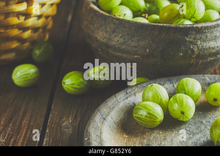 Stachelbeeren auf dunklem Hintergrund in Ton Schüssel und Teller Stockfoto