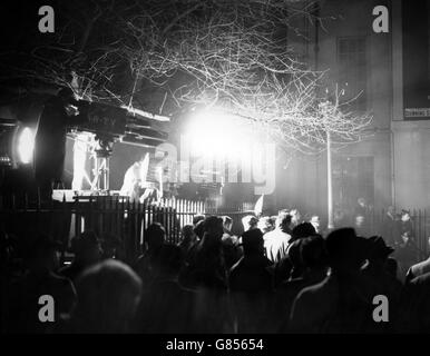 Die Lampen einer Fernseheinheit umschmeicheln die Zuschauer in Londons Downing Street, während der neue Premierminister Harold Macmillan die Führung der britischen Regierung übernimmt. Stockfoto