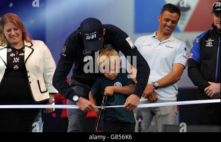 Sir Ben Ainslie, der Skipper von Land Rover BAR, hilft dem örtlichen Schulkind Leo Howard, der die Trophäe dieses Wochenendes entworfen hat, das Band zu schneiden, um den Americas Cup in Portsmouth, Großbritannien, offiziell zu eröffnen. Stockfoto