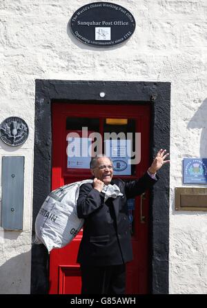 Manzoor Alam, 73, der neue Postmeister der ältesten Post der Welt, winkt, als er am Sanquhar-Postamt in Dumfries und Galloway vorbeigeht. Stockfoto