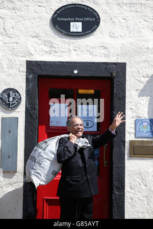 Manzoor Alam, 73, der neue Postmeister der ältesten Post der Welt, winkt, als er am Sanquhar-Postamt in Dumfries und Galloway vorbeigeht. Stockfoto