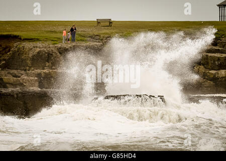 Die Menschen erkunden die Felsen und die Küste von Porthcawl, South Wales, wo starke Winde Großbritannien treffen. Stockfoto