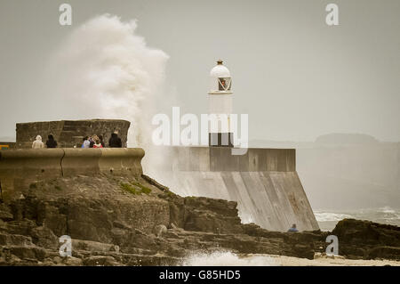 Die Menschen erkunden die Felsen und die Küste an der Hafenmauer in Porthcawl, South Wales, wo starke Winde Großbritannien treffen. Stockfoto