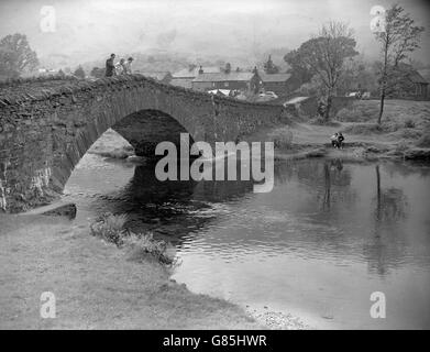 Grange in Borrowdale. Der Fluss Derwent fließt unter der alten Steinbrücke, ein beliebter Aussichtspunkt, um Forellen und gelegentlich Lachs im kalten Wasser zu beobachten, das aus dem Great Gable Berggebiet fließt. Stockfoto