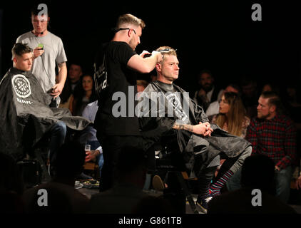 Model Derek Mitchell (rechts), ehemaliger Ehemann von Radio DJ Suzie Maguire, hat seinen Haarschnitt von Alan Beak beim Great British Barber Bash, der im Drygate in Glasgow stattfand. Stockfoto