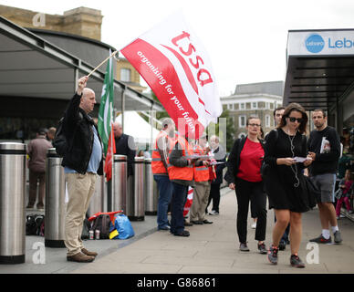 Ein Mitglied der Tssa-Gewerkschaft, das vor dem Bahnhof King's Cross in London streikt, als Pendler und Touristen wegen eines Streiks, der die U-Bahn geschlossen hat, einem Tag voller Reisetäschis gegenüberstehen. Stockfoto