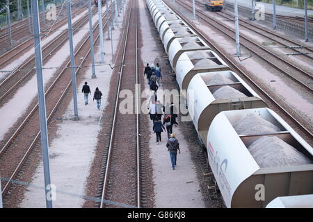 Migranten machen ihren Weg auf Schienen in der Nähe des Eurotunnel-Geländes in Coquelles in Calais, Frankreich. Stockfoto