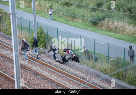 Migranten machen ihren Weg auf Schienen in der Nähe des Eurotunnel-Geländes in Coquelles in Calais, Frankreich. Stockfoto