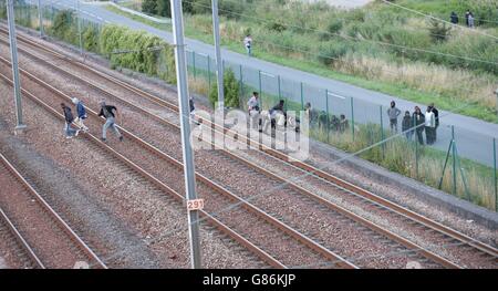 Migranten machen ihren Weg auf Schienen in der Nähe des Eurotunnel-Geländes in Coquelles in Calais, Frankreich. Stockfoto