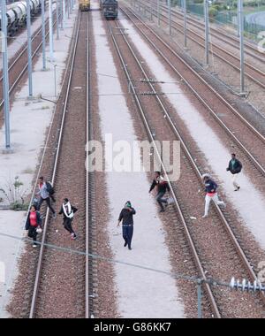 Migranten machen ihren Weg auf Schienen in der Nähe des Eurotunnel-Geländes in Coquelles in Calais, Frankreich. Stockfoto