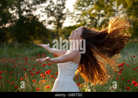 Frau mit ausgestreckten Armen und Haare im Wind wehen Stockfoto