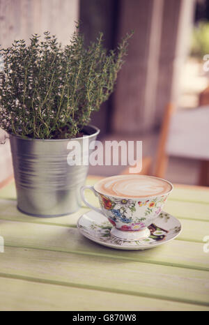 Cappuccio in floral Teetasse neben Thymian Pflanze Stockfoto