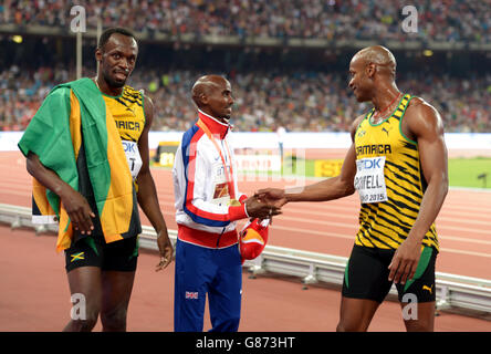 Der britische Mo Farah wird von Jamaikas Usain Bolt (links) und Asafa Powell am achten Tag der IAAF-Weltmeisterschaft im Beijing National Stadium, China, zu seiner Goldmedaille für die 5000 m der Männer gratuliert. Stockfoto