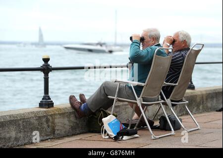 Zwei Zuschauer schauen mit dem Fernglas auf die Boote, die wieder einlaufen, nachdem die Rennen am vierten Tag der Aberdeen Asset Management Cowes Week auf der Isle of Wight aufgrund eines Windmangels aufgegeben wurden. Stockfoto