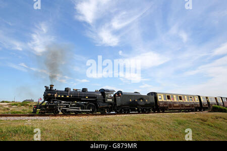 Ein Motor und Waggons der Romney, Hythe und Dymchurch Railway fahren durch das Dungeness Estate in Kent, das als die einzige Wüste Großbritanniens beschrieben wurde und jetzt für £1.5 Millionen verkauft wird. Stockfoto