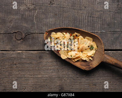 Scheiben von getrocknetem Knoblauch mit würzigen Kräutern auf eine alte gebrauchte Holzlöffel, italienische Küche Zutaten Stockfoto