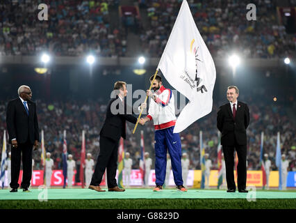 Der britische Kapitän Martyn Rooney erhält die Flagge von Lynn Davies, der britischen Athletics-Präsidentin, als scheidende IAAF-Präsidentin Lamine Diack (links) und Simon Cooper, Head of Sport, Mayor's Office bei Greater London Authority, schauen während des neunten Tages der IAAF-Weltmeisterschaft im Beijing National Stadium, China. Stockfoto