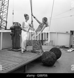 Modell Nikki Ross (links) trägt ein weißes Abendkleid von Frederick starke, während Virginia Bird eine schwarz-weiße Kreation von Frank Usher trägt, während sie an Bord des Frachtflugzeugs Benarmin im Victoria Dock, London, posieren. Beide werden in der kommenden Britischen Woche in Hongkong gezeigt. Stockfoto