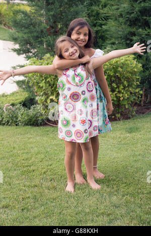 Porträt von zwei lächelnde Mädchen umarmt im Garten Stockfoto