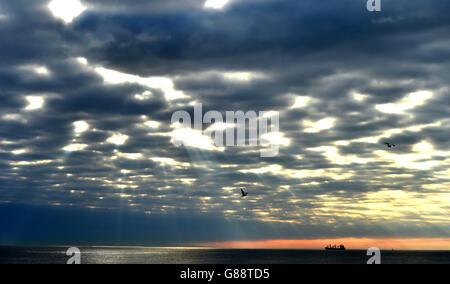 Sonnenstrahlen strahlen strahlen strahlen durch die Wolken auf der Nordsee, während ein Schiff in der Nähe der Mündung der Tyne an diesem Morgen passiert. Stockfoto