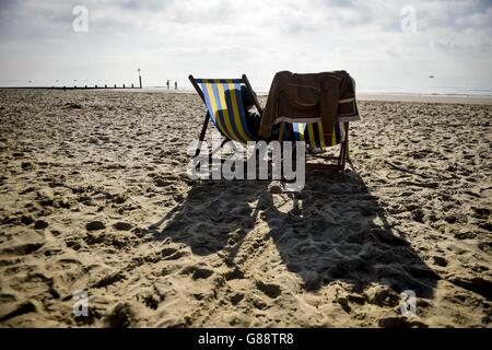 Während des schönen Wetters an der Südküste entspannen sich die Menschen in der warmen Sonne auf den Liegestühlen am Bournemouth Beach. Stockfoto
