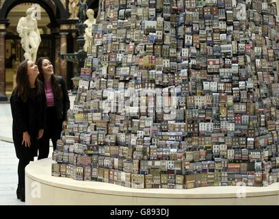 Die Leute sehen den "Turm von Babel" des Künstlers Barnaby Barford, eine sechs Meter hohe Keramikskulptur, die aus 3,000 Einzelstücken besteht, die echte Londoner Ladenfronten darstellen, die in den mittelalterlichen Renaissance-Galerien des V&A Museums ausgestellt sind. Stockfoto