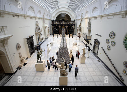 Die Leute sehen den "Turm von Babel" des Künstlers Barnaby Barford, eine sechs Meter hohe Keramikskulptur, die aus 3,000 Einzelstücken besteht, die echte Londoner Ladenfronten darstellen, die in den mittelalterlichen Renaissance-Galerien des V&A Museums ausgestellt sind. Stockfoto