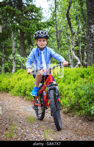 Formell gekleidet junge mit Krawatte, roter Berg Radfahren auf einem Schotterweg in den Wald. Sommer ohne Sonne. Das Tragen eines Helmes. Stockfoto