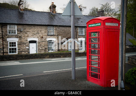 Eine helle rote Telefonzelle umgewandelt zu Haus und Notfall-Defibrillator bei Herzinfarkten, am Straßenrand in Cwrt Dorf, Snowdonia-Nationalpark, Gwynedd, Nord Wales UK Stockfoto