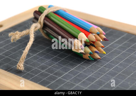Paket von Buntstiften auf einer Tafel auf weißem Hintergrund Stockfoto