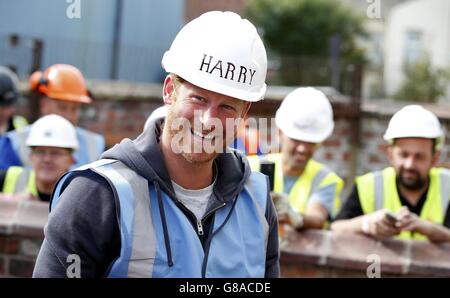 Prinz Harry lächelt, als er sich beim Besuch des DIY SOS-Teams der BBC für das Big Build: Veteran's Special in einer Straße in Manchester auf die Verlegung von Pflasterplatten vorbereitet. Stockfoto