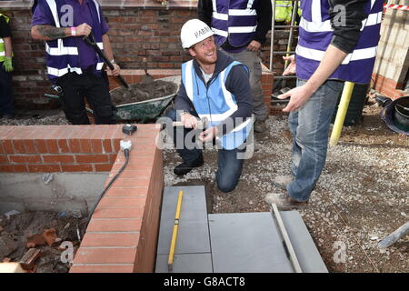 Prinz Harry legt während seines Besuchs beim DIY SOS Team der BBC für The Big Build: Veteran's Special in einer Straße in Manchester Pflasterplatten. Stockfoto