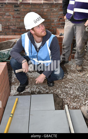 Prinz Harry legt während seines Besuchs beim DIY SOS Team der BBC für The Big Build: Veteran's Special in einer Straße in Manchester Pflasterplatten. Stockfoto