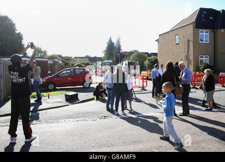 Die Bewohner versuchen, einen genaueren Blick auf eine Sinkhole zu werfen, die sich in einer Wohnstraße in St. Albans eröffnet hat. Stockfoto